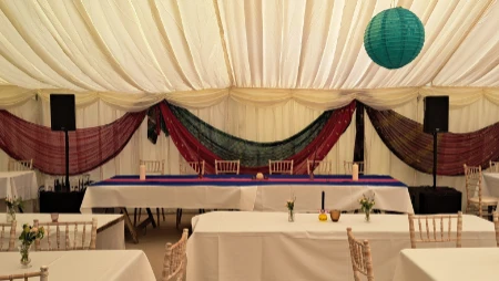 Speakers by top table at wedding in a marque